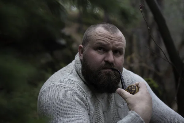 Bearded man smokes a pipe in the wood — Stock Photo, Image