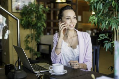 Kafede dinlenme sırasında hücre telefon ve dizüstü bilgisayar kullanan rüya gibi kadın büyüleyici kahvehane iç, taşınabilir net-kitap ile oturan genç güzel kadın