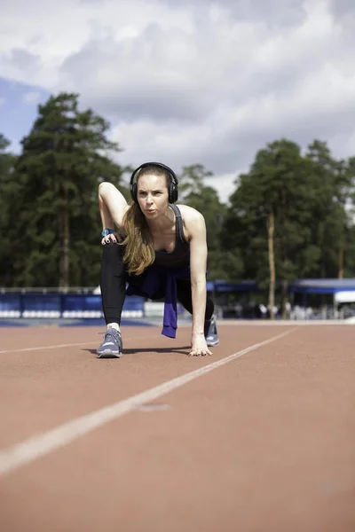 Mujer atlética estirando sus músculos antes de trotar en la pista — Foto de Stock