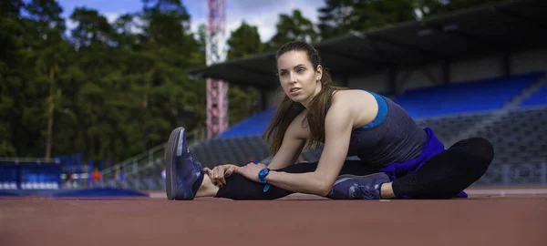 Mujer atlética estirando sus músculos antes de trotar en la pista — Foto de Stock