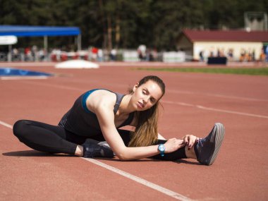 Atletik kadın yolda koşu önce kasları germe