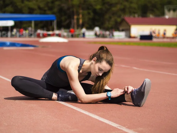 Mujer atlética estirando sus músculos antes de trotar en la pista — Foto de Stock