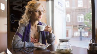 Genç güzel kadın kafe küçük masada oturur.