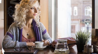 Genç güzel kadın kafe küçük masada oturur.