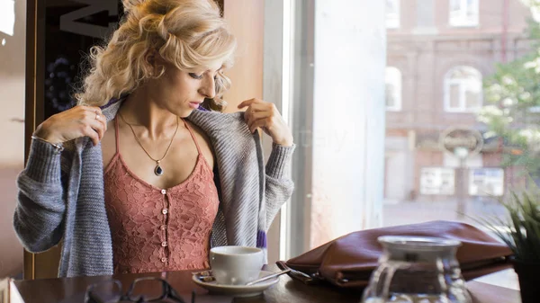Joven hermosa mujer se sienta en la mesita en la cafetería . — Foto de Stock