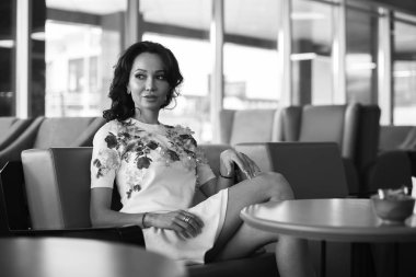 Genç kadın kapalı kentsel kafede oturan onun smartphone içme kahve ve kullanım. Cafe city yaşam tarzı. Güzel kız rahat portresi. Siyah ve beyaz