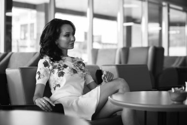 Genç kadın kapalı kentsel kafede oturan onun smartphone içme kahve ve kullanım. Cafe city yaşam tarzı. Güzel kız rahat portresi. Siyah ve beyaz