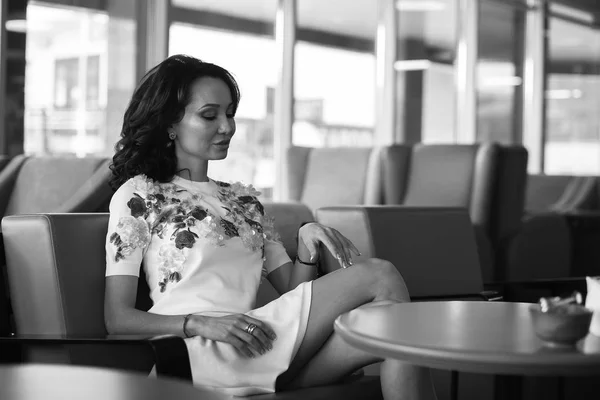 Young woman drinking coffee and use her smartphone sitting indoor in urban cafe. Cafe city lifestyle. Casual portrait of beautiful girl. Black and white — Stock Photo, Image