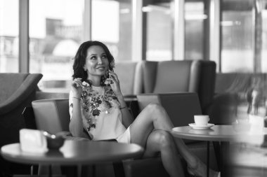 Genç kadın kapalı kentsel kafede oturan onun smartphone içme kahve ve kullanım. Cafe city yaşam tarzı. Güzel kız rahat portresi. Siyah ve beyaz