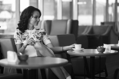 Genç kadın kapalı kentsel kafede oturan onun smartphone içme kahve ve kullanım. Cafe city yaşam tarzı. Güzel kız rahat portresi. Siyah ve beyaz