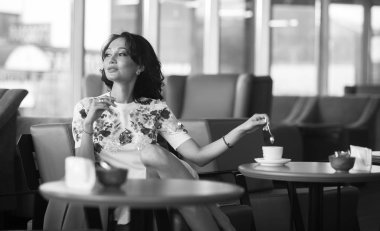 Genç kadın kapalı kentsel kafede oturan onun smartphone içme kahve ve kullanım. Cafe city yaşam tarzı. Güzel kız rahat portresi. Siyah ve beyaz