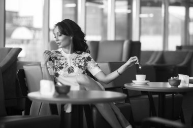 Genç kadın kapalı kentsel kafede oturan onun smartphone içme kahve ve kullanım. Cafe city yaşam tarzı. Güzel kız rahat portresi. Siyah ve beyaz
