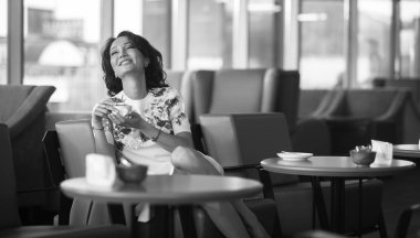 Genç kadın kapalı kentsel kafede oturan onun smartphone içme kahve ve kullanım. Cafe city yaşam tarzı. Güzel kız rahat portresi. Siyah ve beyaz