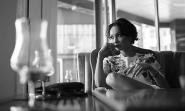 Genç kadın kapalı kentsel kafede oturan onun smartphone içme kahve ve kullanım. Cafe city yaşam tarzı. Güzel kız rahat portresi. Siyah ve beyaz