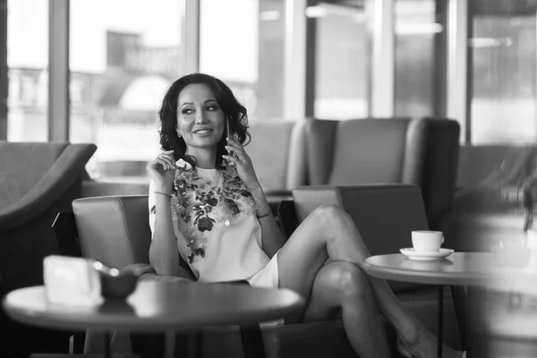 Young woman drinking coffee and use her smartphone sitting indoor in urban cafe. Cafe city lifestyle. Casual portrait of beautiful girl. Black and white — Stock Photo, Image