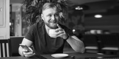 Beyaz adam onun smartphone kafe ve içecek çay otururken kullanın. Siyah ve beyaz fotoğraf. Eski Hollywood tarzı.