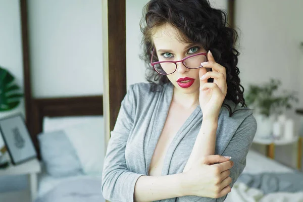Sexy girl with glasses and book in lingerie sits on the bed — Stock Photo, Image