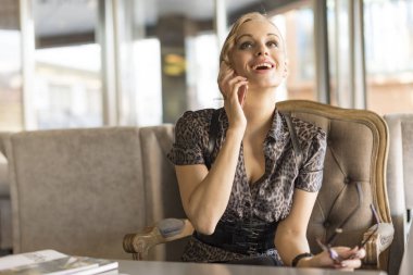 Genç ve güzel kadın imajıyla telefonu konuşurken kafede gülüyor kahve