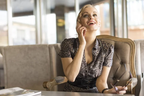 Genç ve güzel kadın imajıyla telefonu konuşurken kafede gülüyor kahve