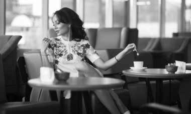 Genç kadın kapalı kentsel kafede oturan onun smartphone içme kahve ve kullanım. Cafe city yaşam tarzı. Güzel kız rahat portresi. Siyah ve beyaz