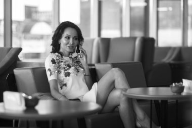 Genç kadın kapalı kentsel kafede oturan onun smartphone içme kahve ve kullanım. Cafe city yaşam tarzı. Güzel kız rahat portresi. Siyah ve beyaz