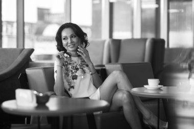 Genç kadın kapalı kentsel kafede oturan onun smartphone içme kahve ve kullanım. Cafe city yaşam tarzı. Güzel kız rahat portresi. Siyah ve beyaz