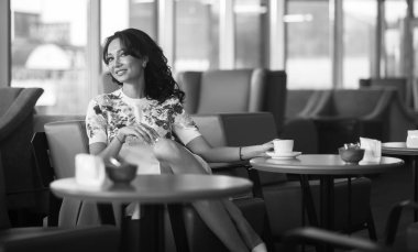 Genç kadın kapalı kentsel kafede oturan onun smartphone içme kahve ve kullanım. Cafe city yaşam tarzı. Güzel kız rahat portresi. Siyah ve beyaz