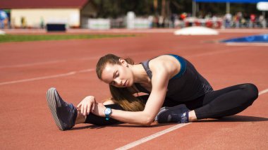 Atletik kadın yolda koşu önce kasları germe