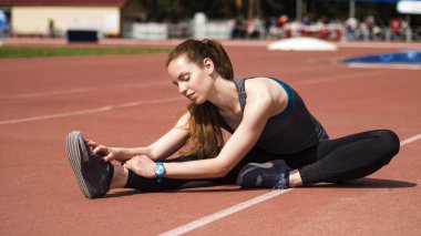 Atletik kadın yolda koşu önce kasları germe