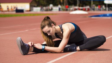 Atletik kadın yolda koşu önce kasları germe
