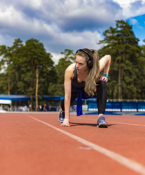 Mujer atlética estirando sus músculos antes de trotar en la pista — Foto de Stock