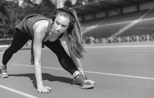 Mujer atlética estirando sus músculos antes de trotar en la pista — Foto de Stock