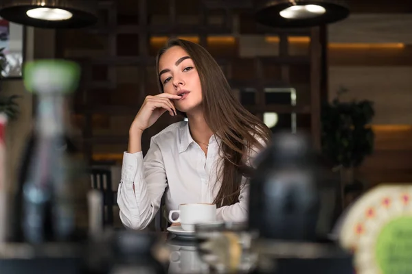 Young Business woman in white shirt drinking a cup of coffee in a cafe and flirts