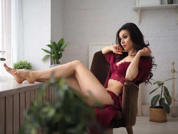 Bella e premurosa donna seduta sul bracciale in lingerie rossa. Risveglio sensuale . — Foto Stock