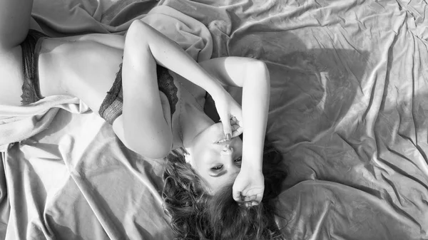 非常にセクシーな女性下着を着てベッドに横になっています。官能的なウェイク アップ、モノクロ画像 — ストック写真
