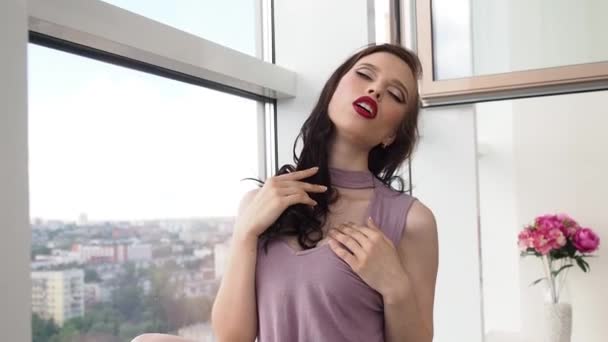 Mujer sexy se sienta al lado de la ventana y los labios de tacto, cuello — Vídeo de stock