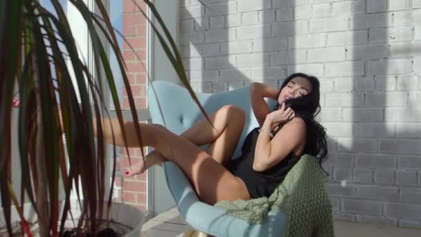 Sexy bruneta sedí na křesle a táhnoucí se brzy ráno — Stock video