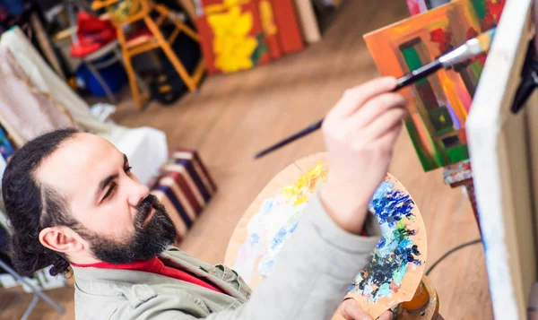 Nahaufnahme eines Malers, der in seinem Atelier auf einer modernen abstrakten Ölleinwand arbeitet — Stockfoto