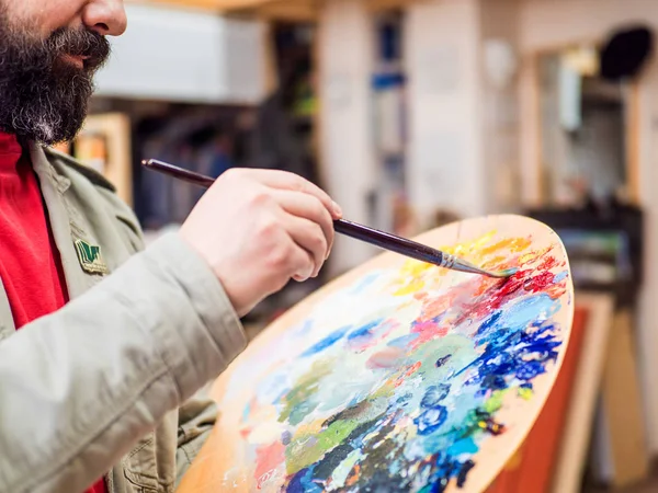 Close-up van schilder kunstenaar Meng de verven en werken in een moderne abstracte olie doek in zijn atelier — Stockfoto