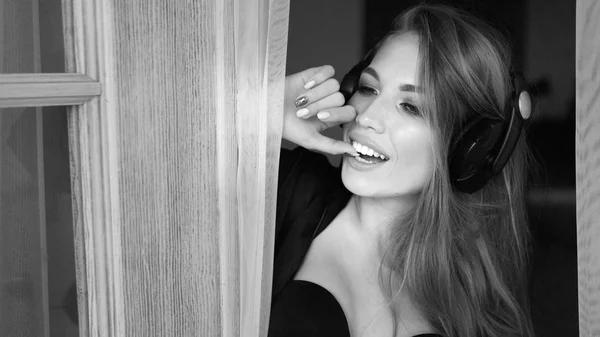 Femme sexy écoutant la musique dans les écouteurs. Elle porte une lingerie en dentelle noire et une robe de chambre en soie. Image en noir et blanc . — Photo