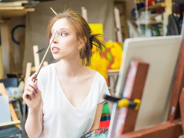 Молодая женщина художник в фартуке картина на холсте в художественной студии — стоковое фото