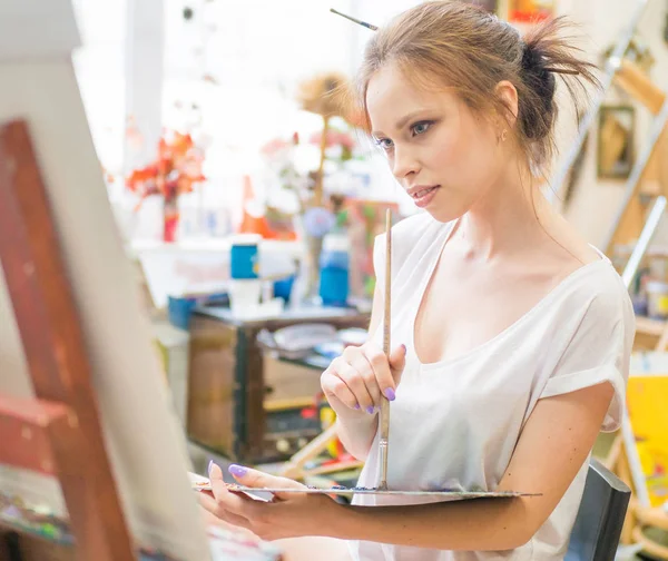 Artista pinta quadro sobre tela com tintas a óleo em estúdio em casa — Fotografia de Stock