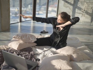 Müzik dinlerken üstünde belgili tanımlık yatak ve dansing dizüstü bilgisayar kullanan genç kadın