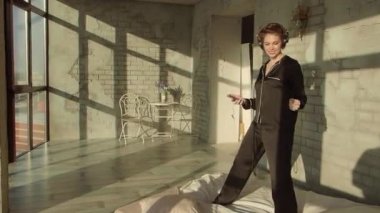 Bir telefon ve kulaklık kullanarak favori müzik. müzik fan hafta sonu ruh sabah. Güneşli yatak odası. Çarşaf, yastık, ekose ve pijama. Video görüntüleri.