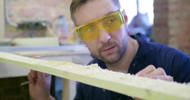 Homem Uma Loja Carpintaria Sopra Serragem Placa Olha Para Qualidade — Vídeo de Stock