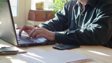 Akıllı telefon ve dizüstü bilgisayar kullanarak evden çalışan genç bir adam çekim silüeti kırpılmış, adamın elleri akıllı kullanarak Ardiles, adam onun İşyerinde teknoloji, parlama ışık kullanarak telefon