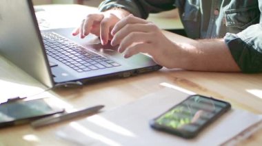 Adamın elleri ev içi masasında boş ekranlı dizüstü bilgisayar kullanıyor.