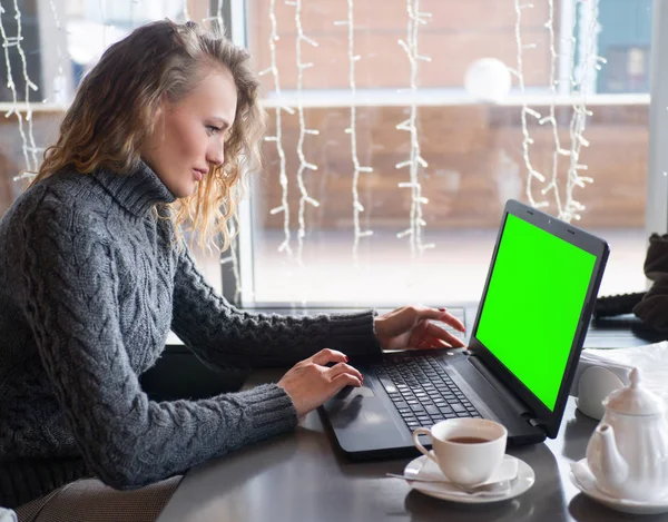 Πορτρέτο του μια νεαρή όμορφη επιχειρηματίες απολαμβάνοντας καφέ κατά τη διάρκεια εργασιών στην οθόνη του υπολογιστή, πράσινο φορητό lap-top — Φωτογραφία Αρχείου