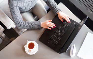 Dizüstü bilgisayarda yazarak eller kadın. bir fincan çay. Görünümü.