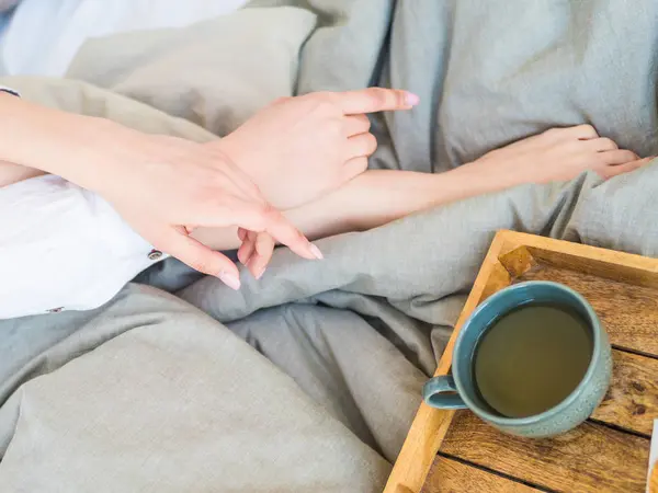 Coffee in bed. shapely female legs in warm socks, wooden tray for breakfast in bed. two cups of coffee and marshmallows. the concept of cozy home. top view — Stock Photo, Image